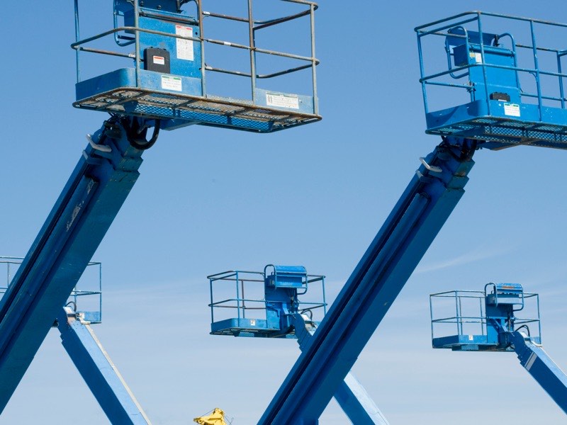 Scissor lifts raised against the sky